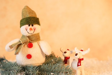 Photo of Funny snowman and deer figures with fir branch on artificial snow