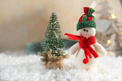 Photo of Funny snowman figure and decorative Christmas tree on artificial snow