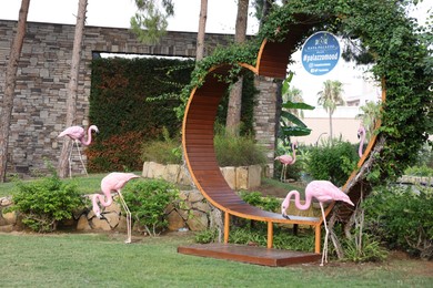 Photo of Belek, Turkey - July 25, 2024: Wooden bench in shape of heart and decorative flamingos outdoors