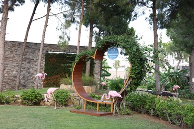 Belek, Turkey - July 25, 2024: Wooden bench in shape of heart and decorative flamingos outdoors