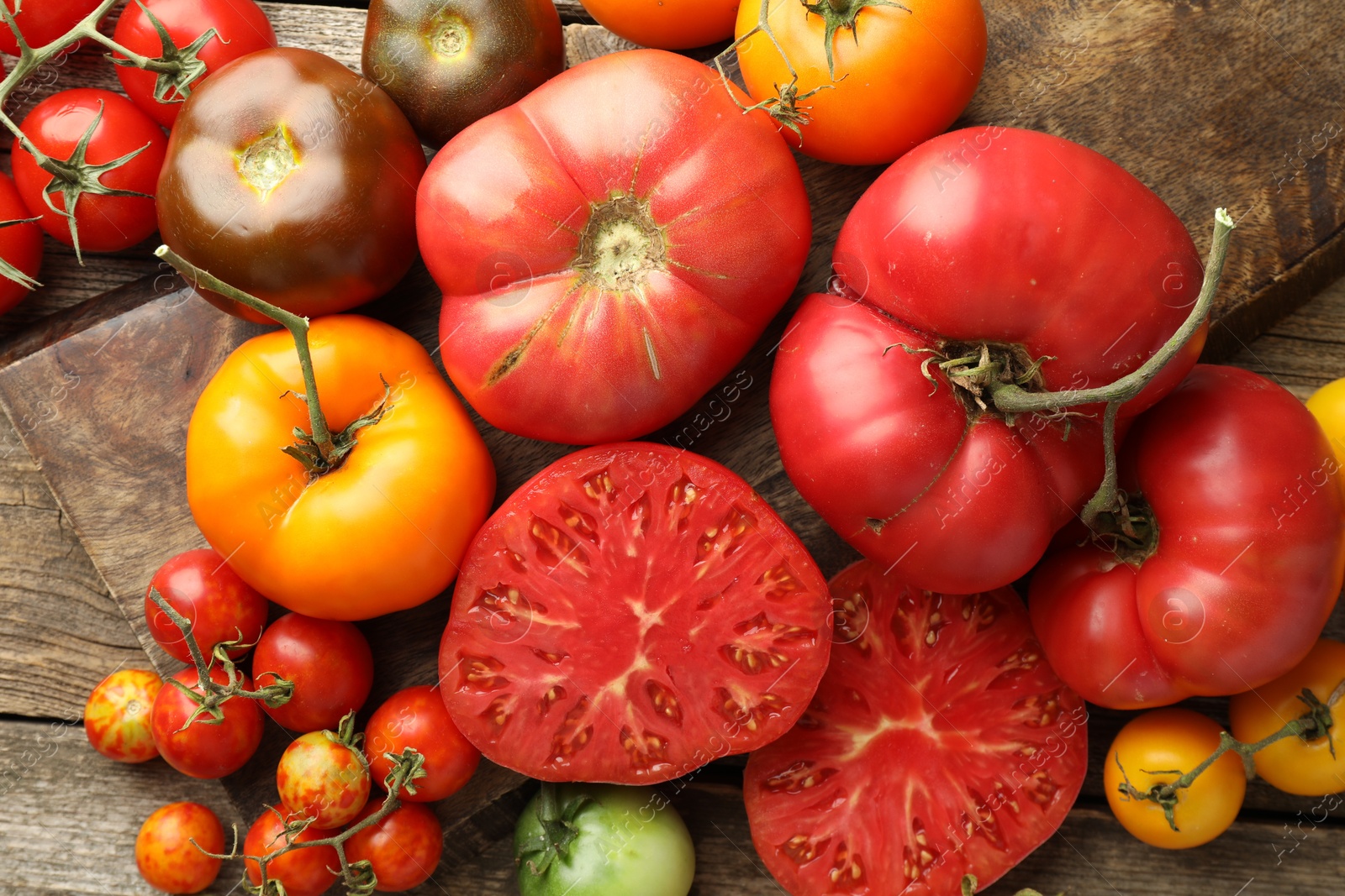 Photo of Different ripe tomatoes on wooden table, top view