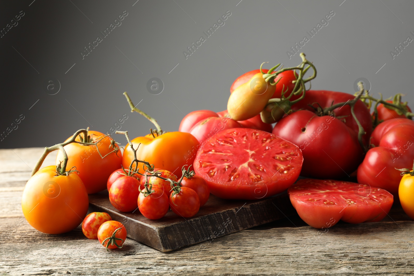 Photo of Many different ripe tomatoes on wooden table