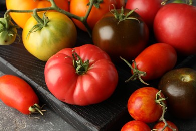 Different ripe tomatoes on grey table, closeup