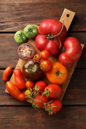 Photo of Different ripe tomatoes on wooden table, top view