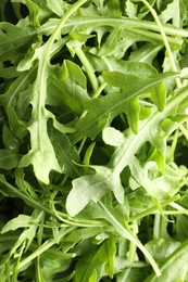 Photo of Many fresh arugula leaves with water drops as background, above view