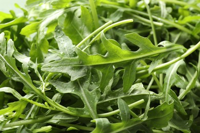 Photo of Many fresh arugula leaves with water drops as background, closeup