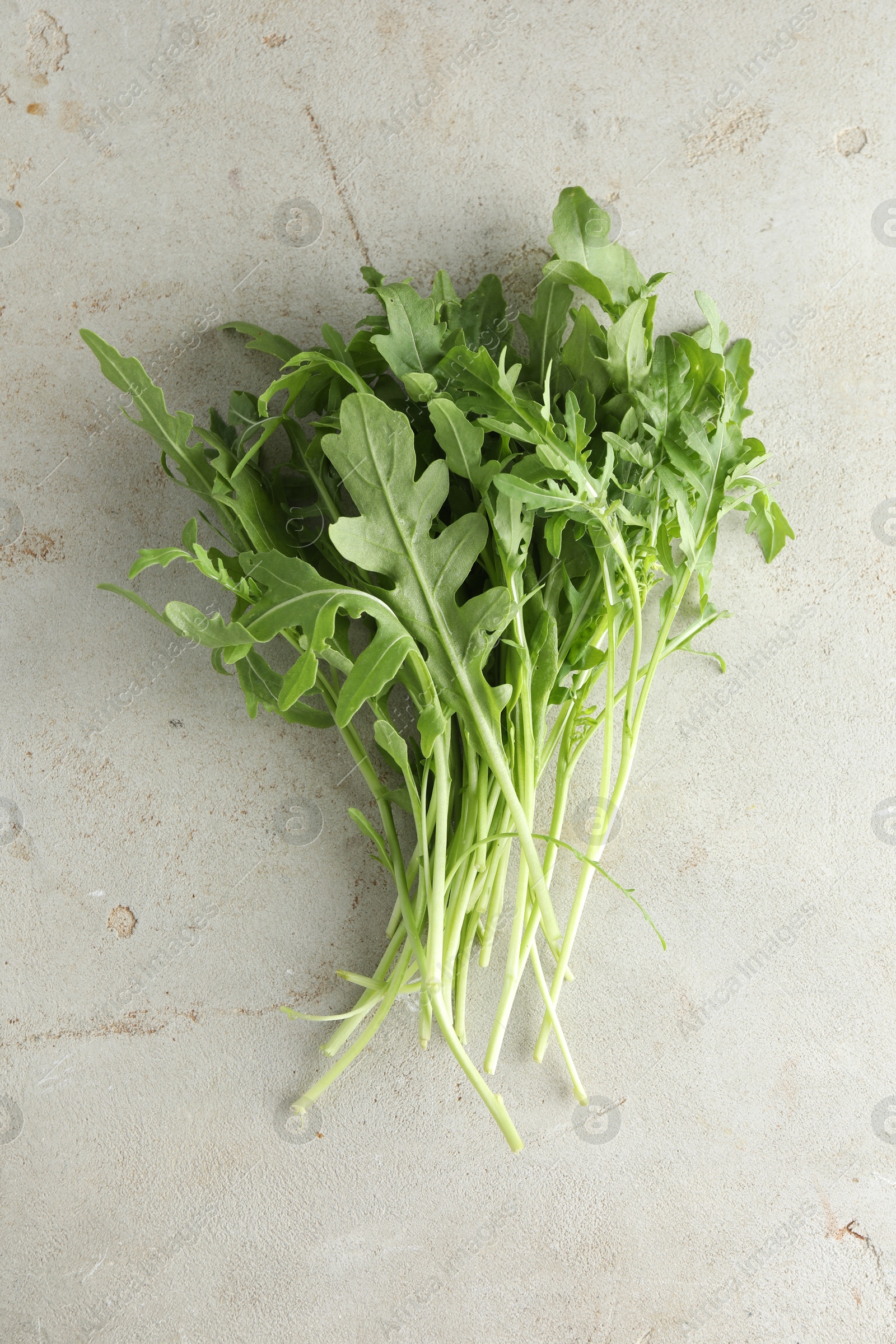 Photo of Many fresh arugula leaves on grey textured table, top view