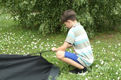 Photo of Little boy setting up camping tent outdoors