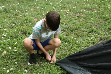 Photo of Little boy setting up camping tent outdoors