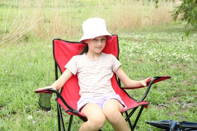 Photo of Cute girl resting in camping chair outdoors