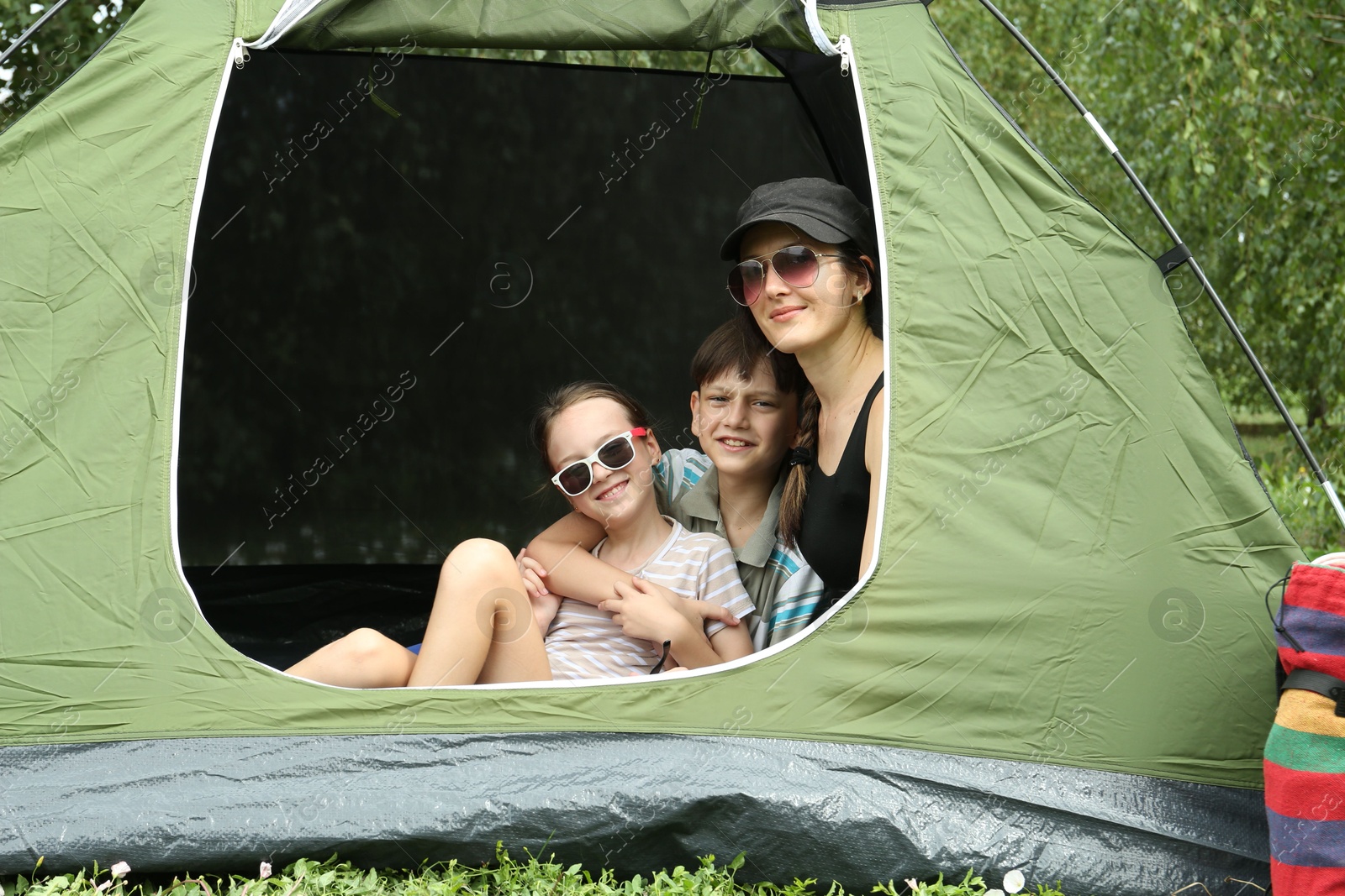 Photo of Mother and her kids resting in camping tent outdoors