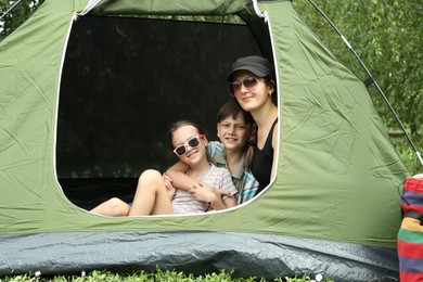 Photo of Mother and her kids resting in camping tent outdoors