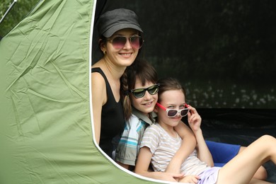 Mother and her kids resting in camping tent outdoors