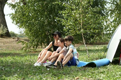 Photo of Mother and her kids spending time together near camping tent outdoors