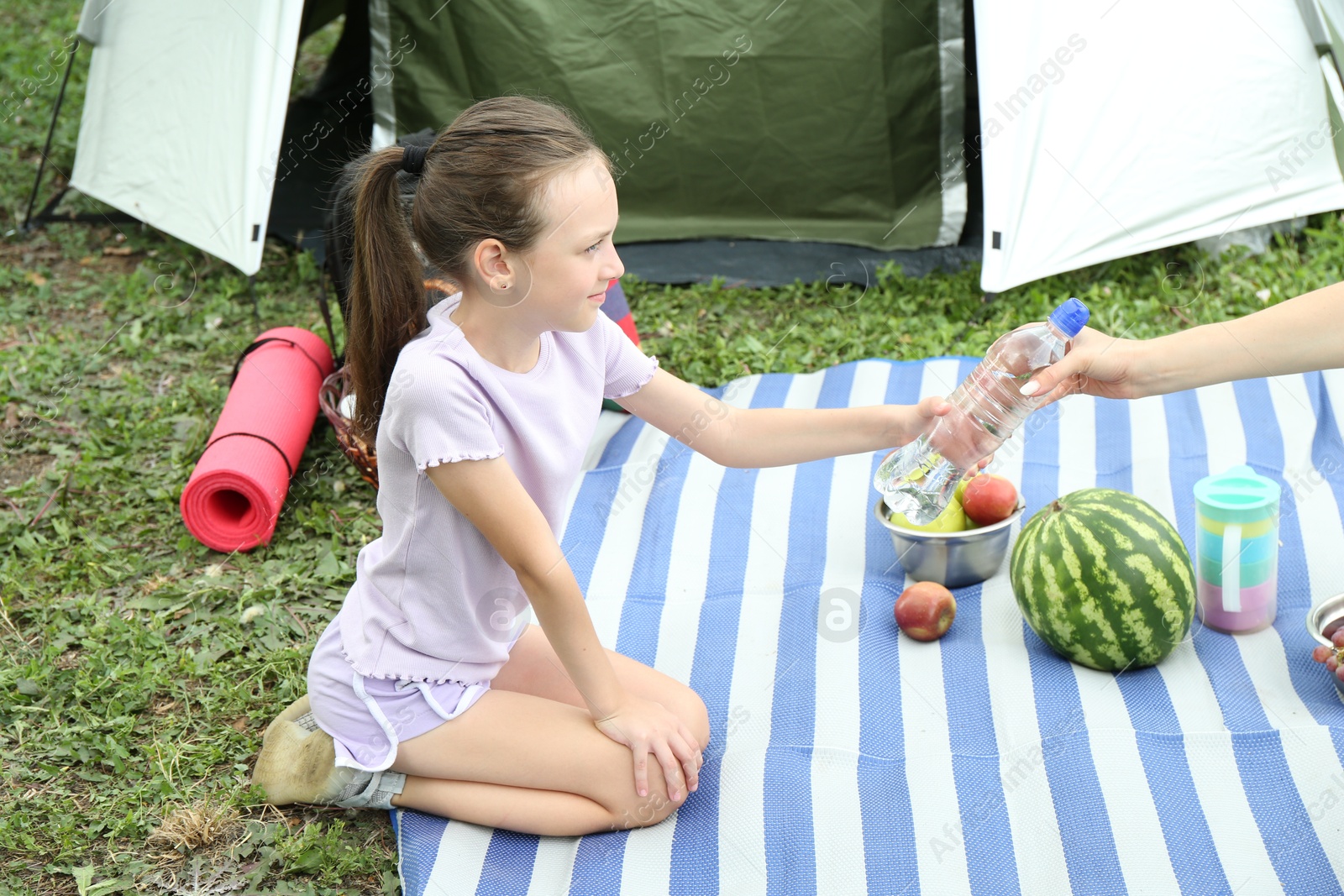 Photo of Mother and her daughter having picnic near camping tent outdoors