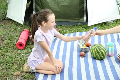 Photo of Mother and her daughter having picnic near camping tent outdoors