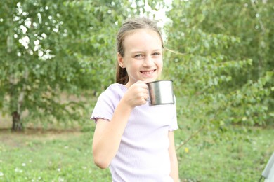 Cute girl with metal mug outdoors. Camping season