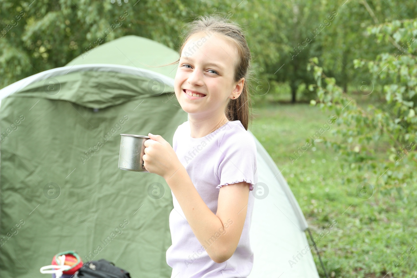 Photo of Cute girl with metal mug outdoors. Camping season