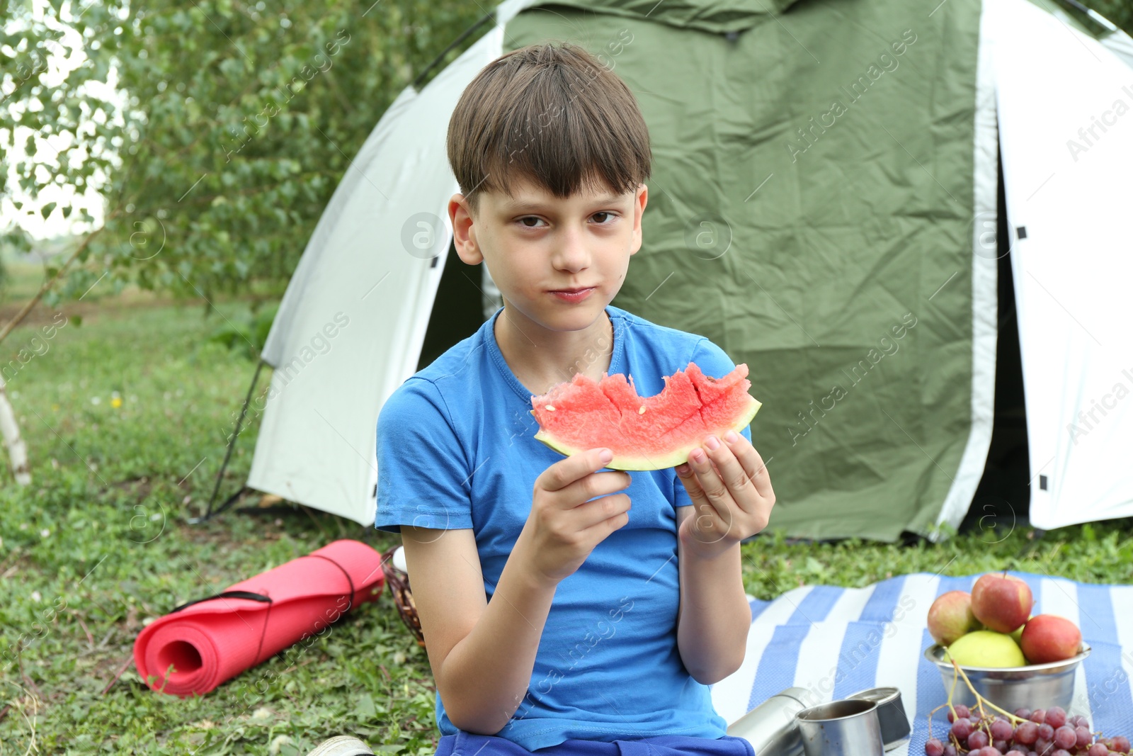 Photo of Boy with slice of fresh watermelon outdoors. Camping season