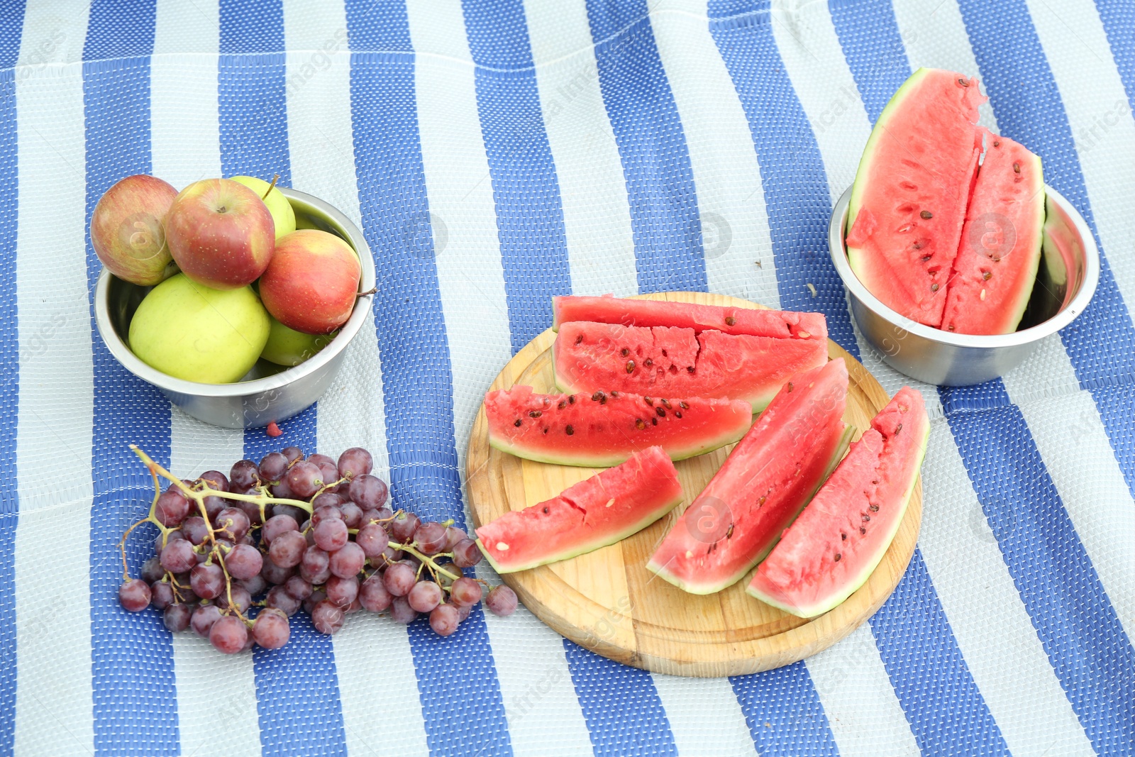 Photo of Fresh watermelon, grapes and apples on blanket