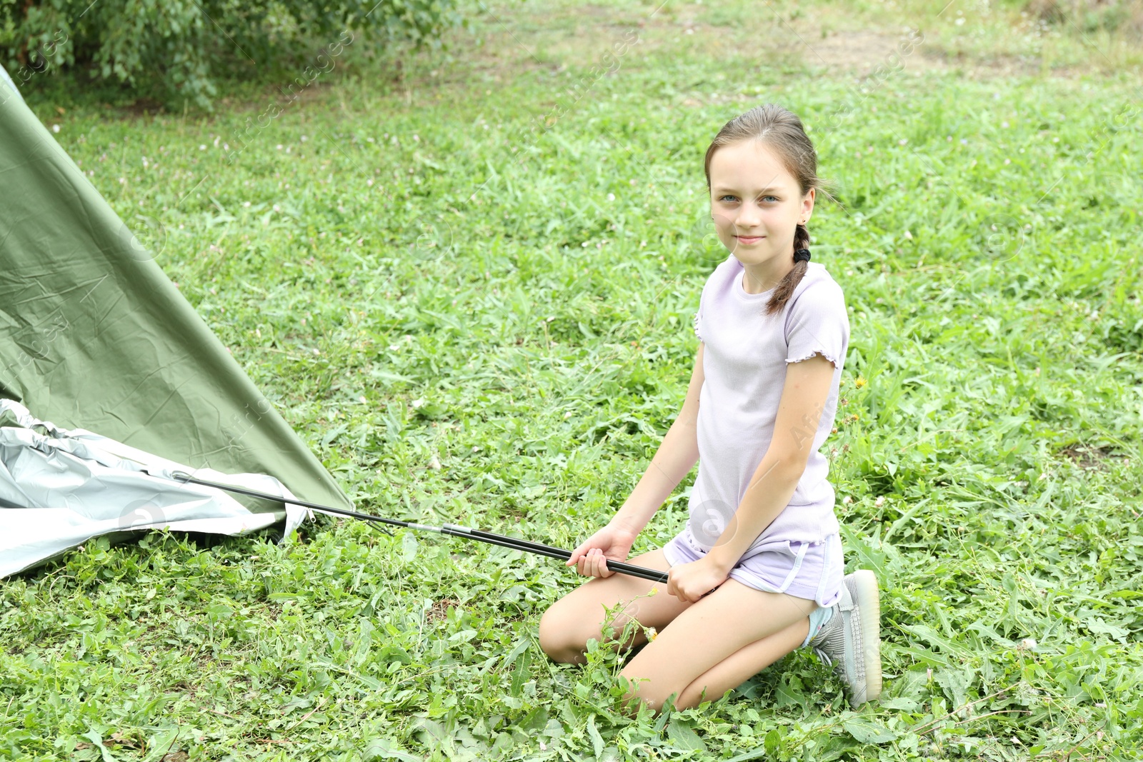 Photo of Little girl setting up camping tent outdoors