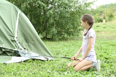 Photo of Little girl setting up camping tent outdoors