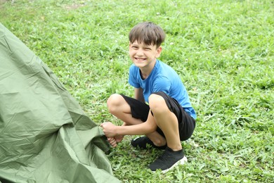 Boy setting up tent outdoors. Camping season