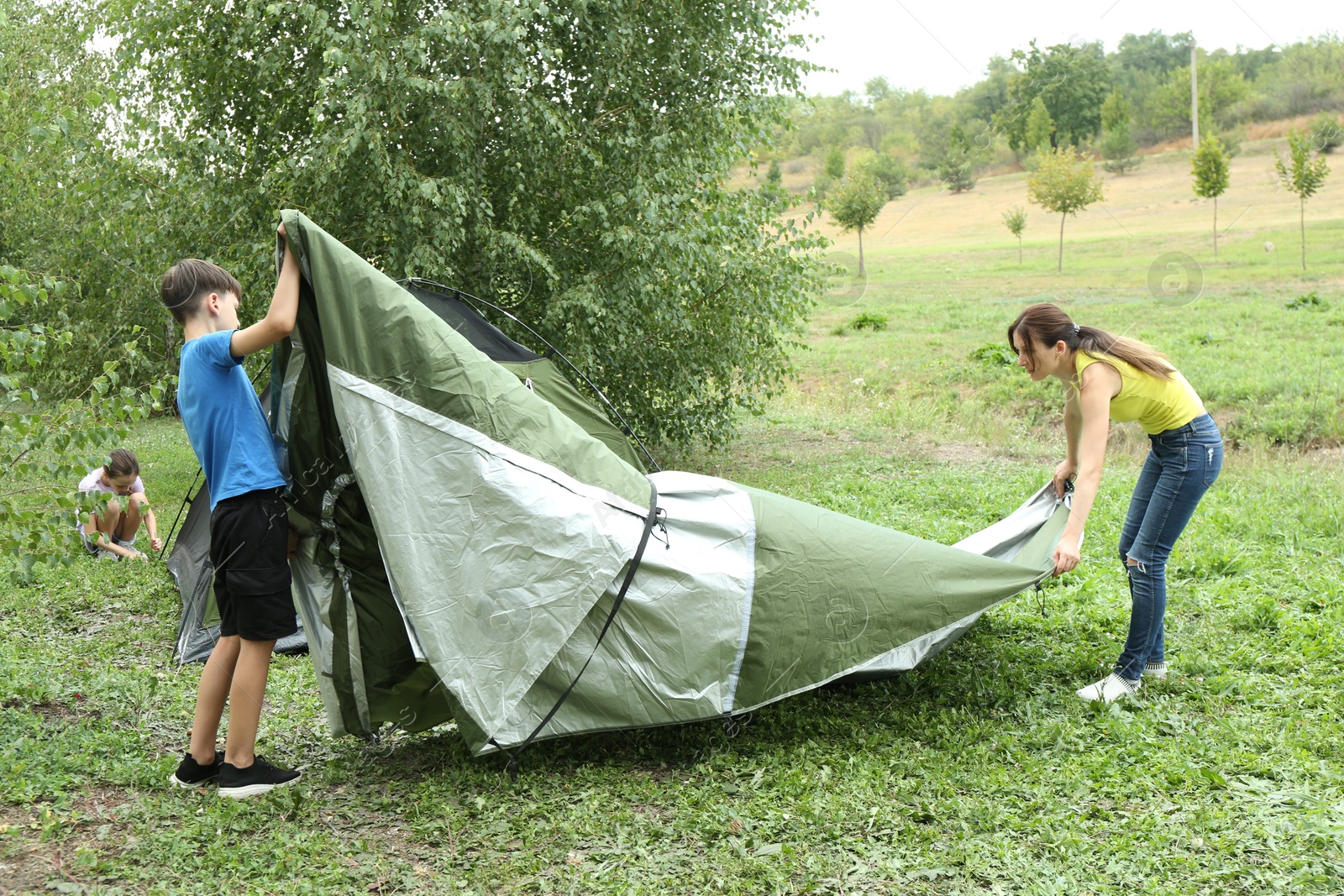 Photo of Mother and her kids setting up camping tent outdoors