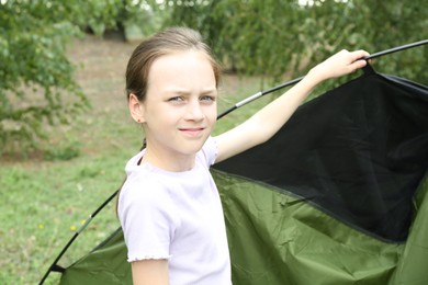 Photo of Little girl setting up camping tent outdoors