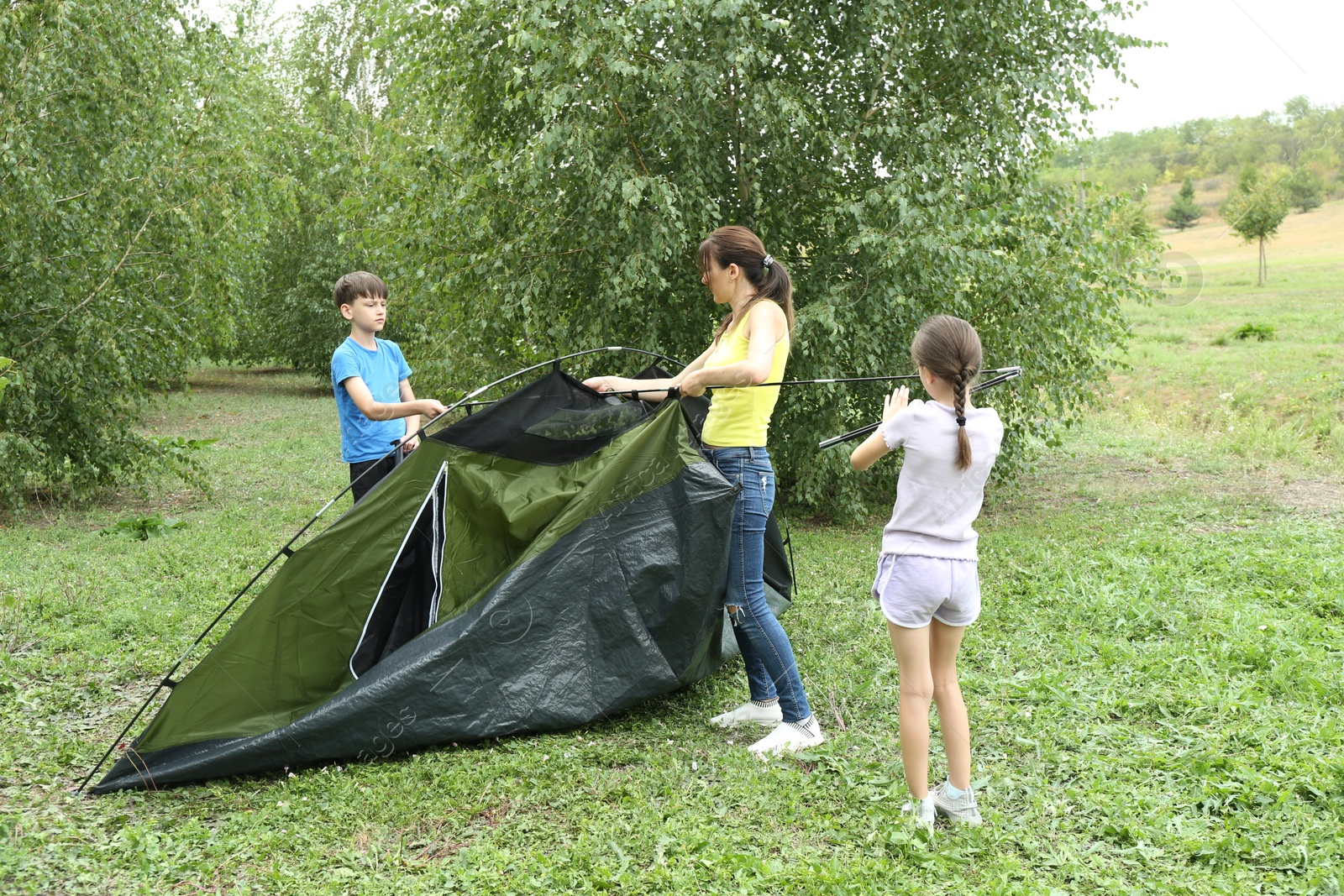 Photo of Mother and her kids setting up camping tent outdoors