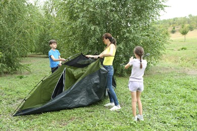 Photo of Mother and her kids setting up camping tent outdoors