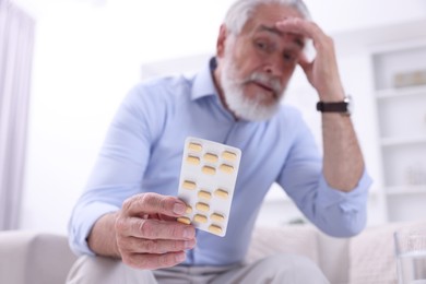 Photo of Senior man with pills at home, selective focus