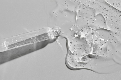 Photo of Dripping cosmetic serum from pipette on grey background, top view