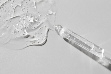 Photo of Dripping cosmetic serum from pipette on grey background, top view