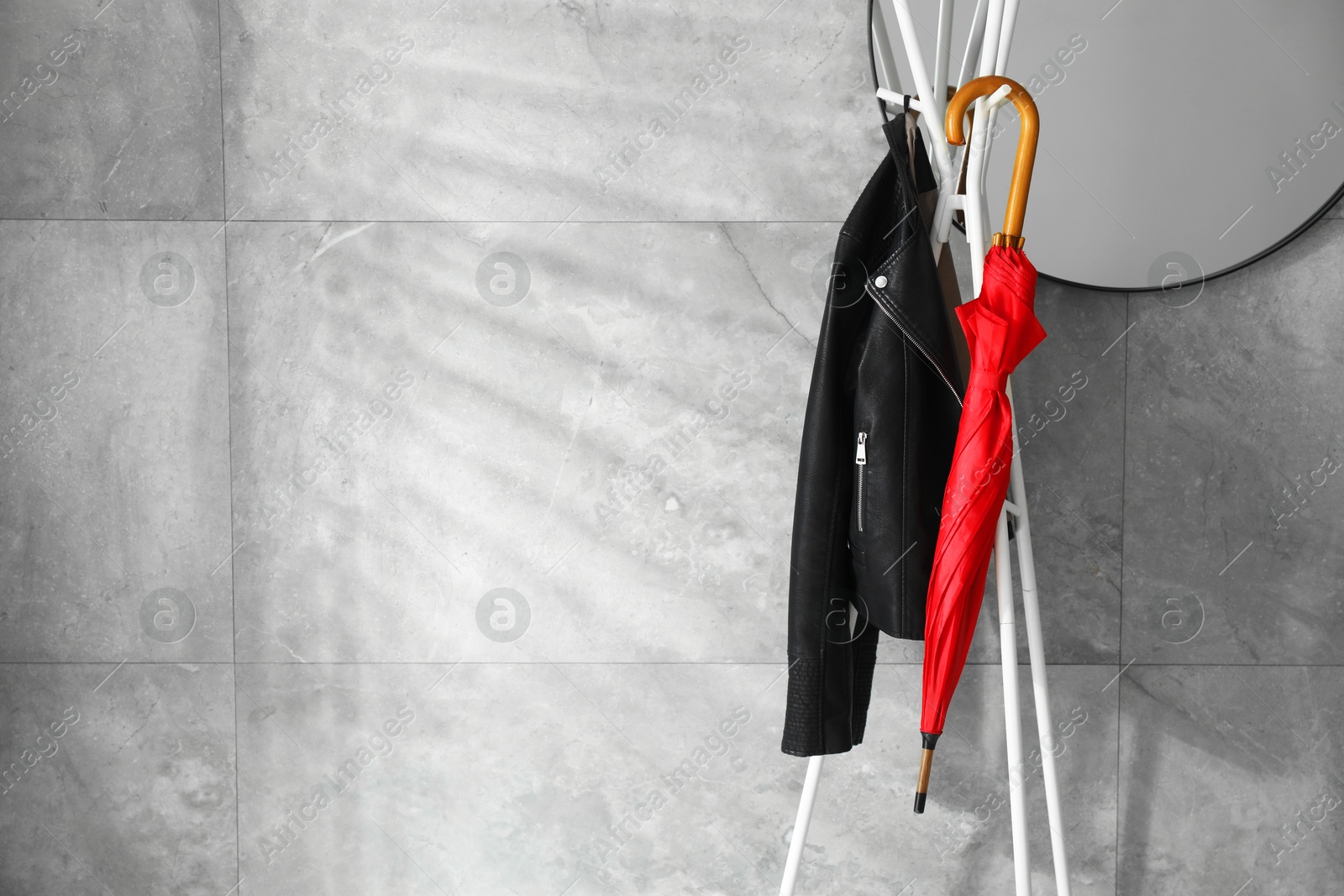 Photo of Red umbrella and jacket on clothing rack near mirror indoors. Space for text