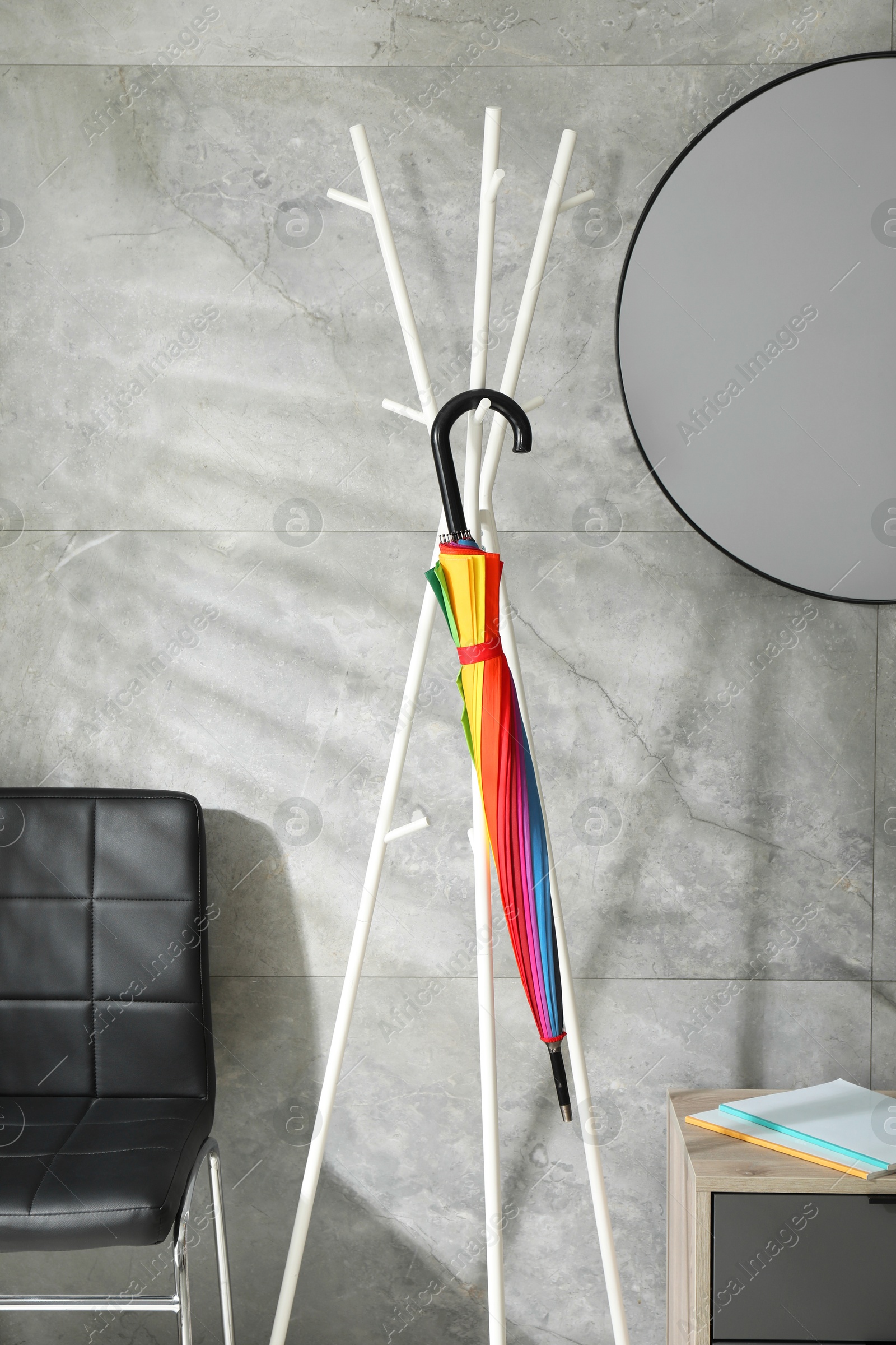 Photo of Bright umbrella on clothing rack at home