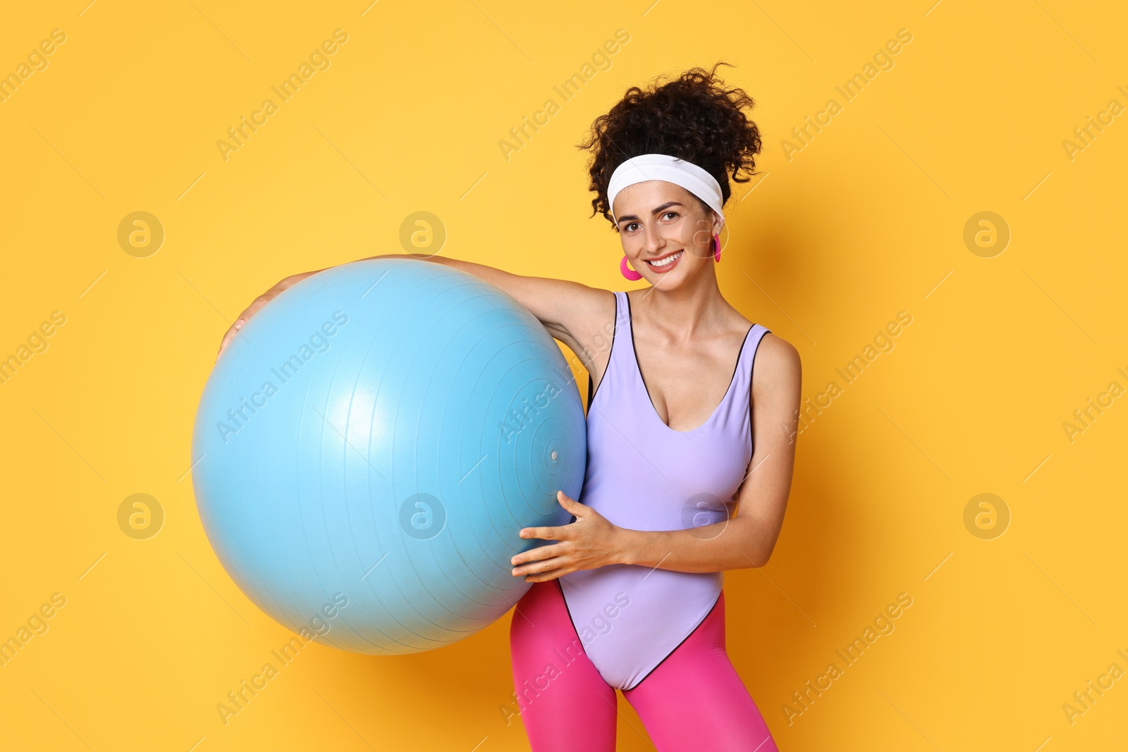 Photo of Aerobics. Woman with fitness ball on orange background