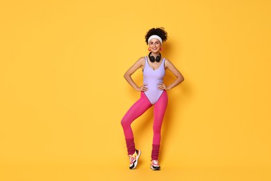 Photo of Happy woman with headphones on orange background