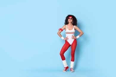 Happy woman in sportswear on light blue background