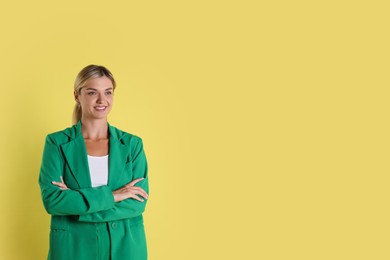 Beautiful woman in stylish green suit on yellow background, space for text