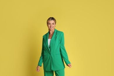 Photo of Beautiful woman in stylish green suit on yellow background