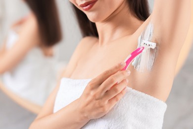 Photo of Woman shaving armpit indoors, closeup. Depilation procedure