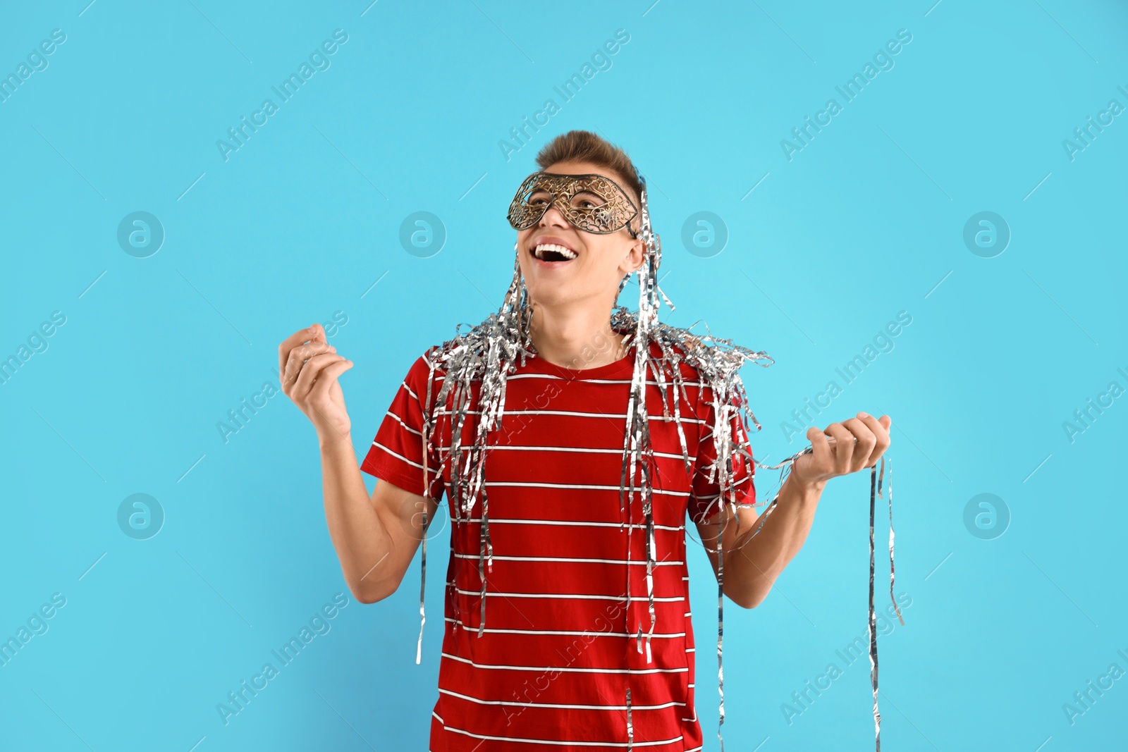 Photo of Charming young man wearing carnival mask on light blue background