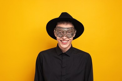 Charming young man wearing carnival mask on orange background