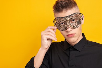 Photo of Charming young man wearing carnival mask on orange background