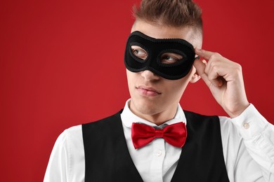 Photo of Charming young man wearing carnival mask on red background