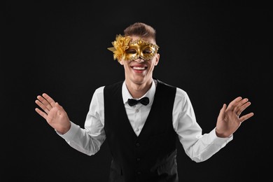 Charming young man wearing carnival mask on black background