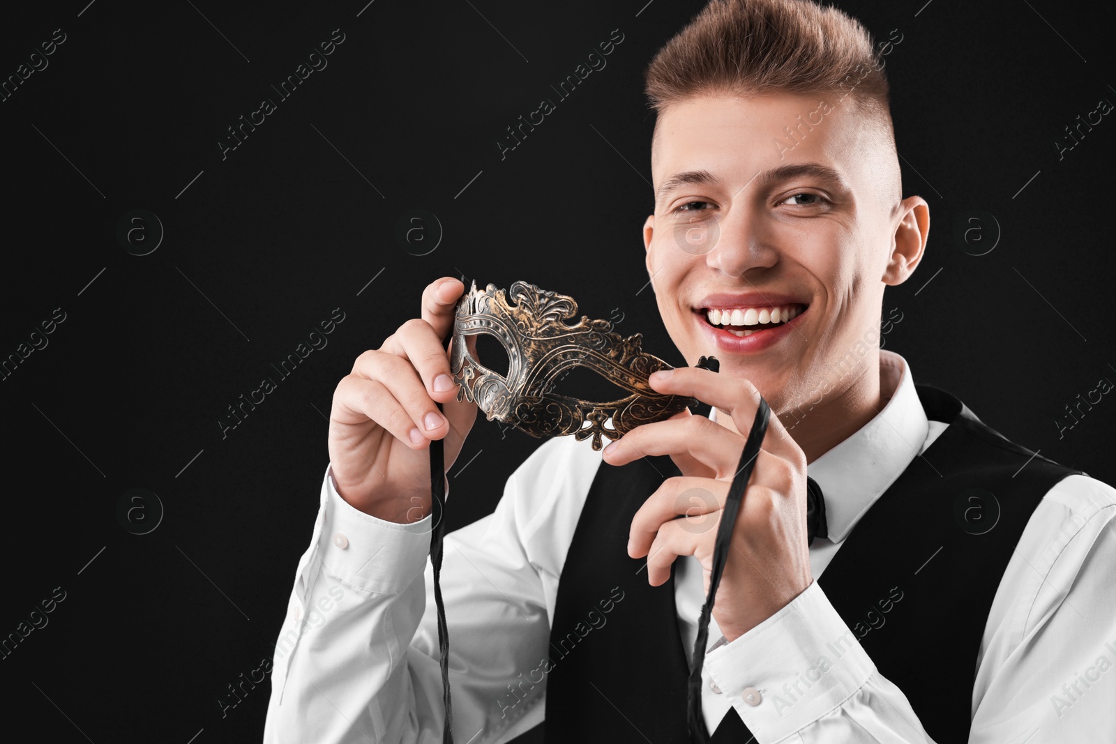 Photo of Charming young man with carnival mask on black background