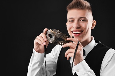 Photo of Charming young man with carnival mask on black background