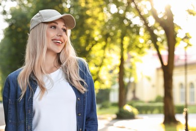 Portrait of smiling woman in baseball cap outdoors, space for text